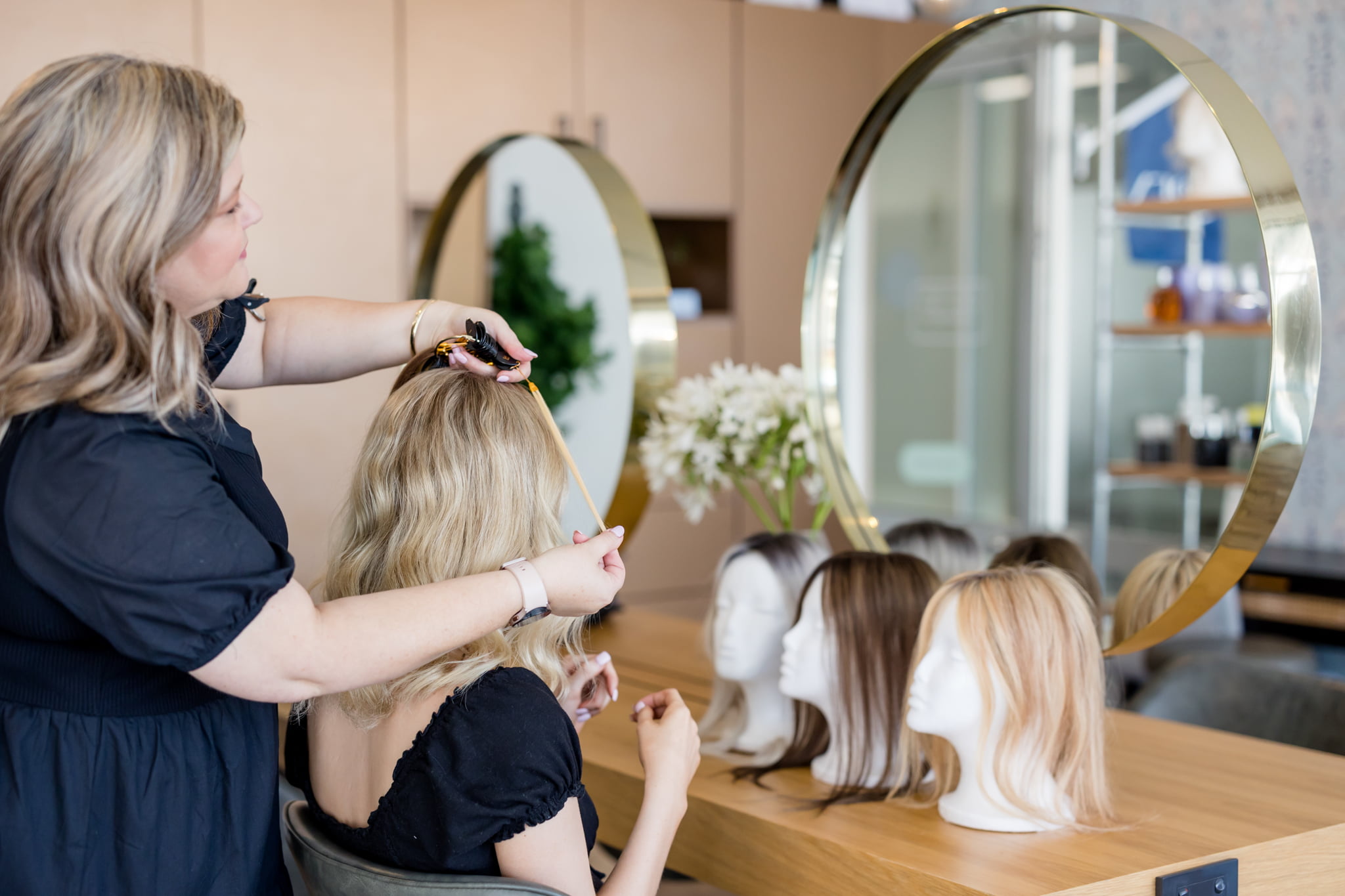 Human hair toppers on styling heads at the round mirror in the Solo Tú studio in Orange NSW